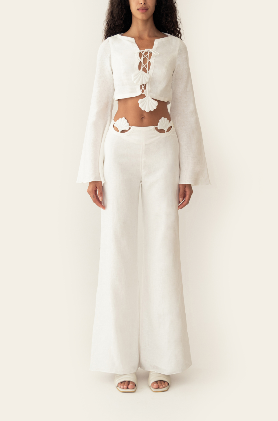 Azulu Amelie Pants in white linen, front view of the relaxed low-rise wide-leg trousers worn with the matching lace-up crop top